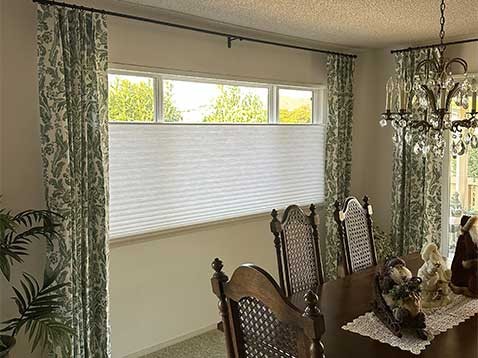 Dining Room with a large window covered by shades and drapes