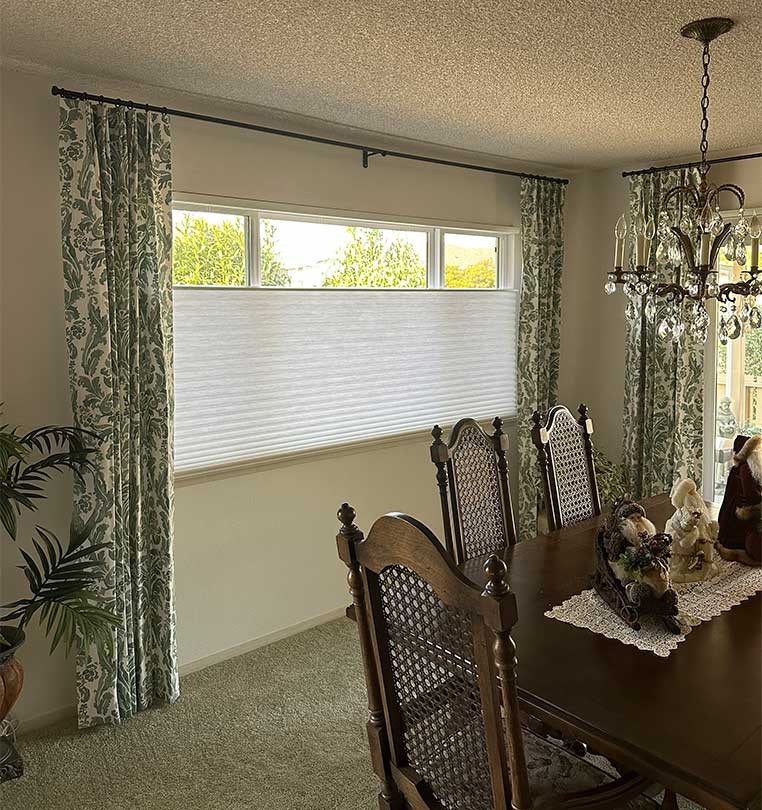 Dining Room with a large window covered by shades and drapes